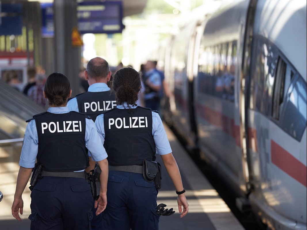 Polizisten gehen an einem Bahnsteig entlang.