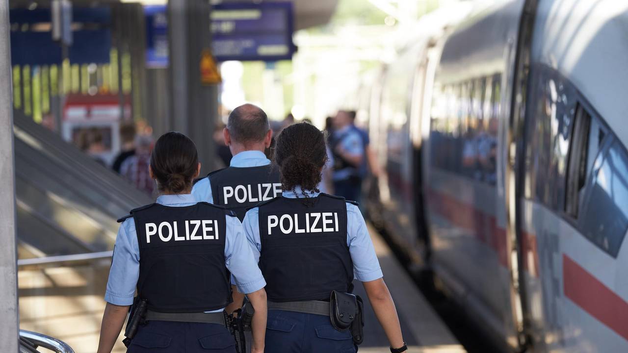 Polizisten gehen an einem Bahnsteig entlang.