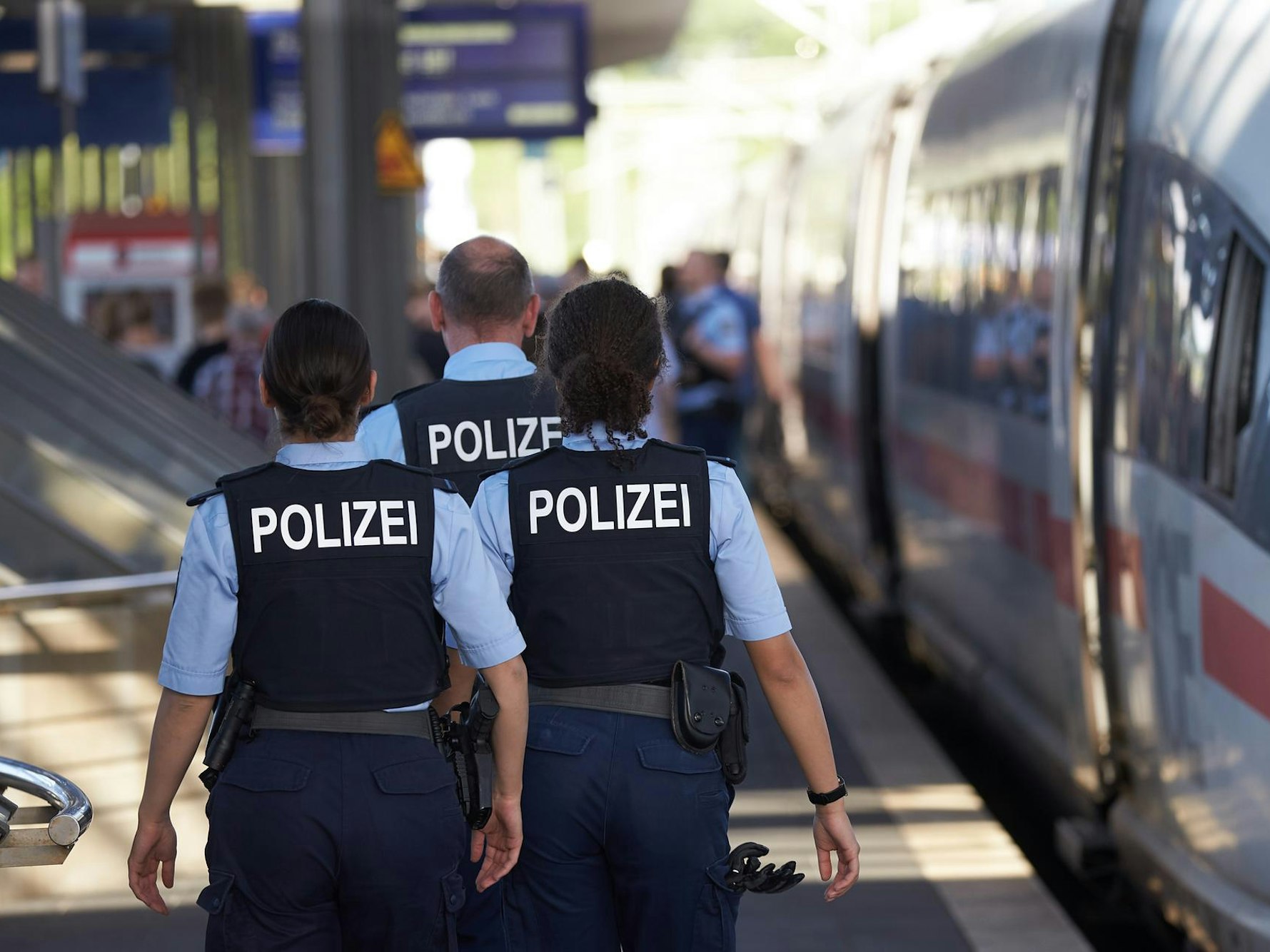 Polizisten gehen an einem Bahnsteig entlang.
