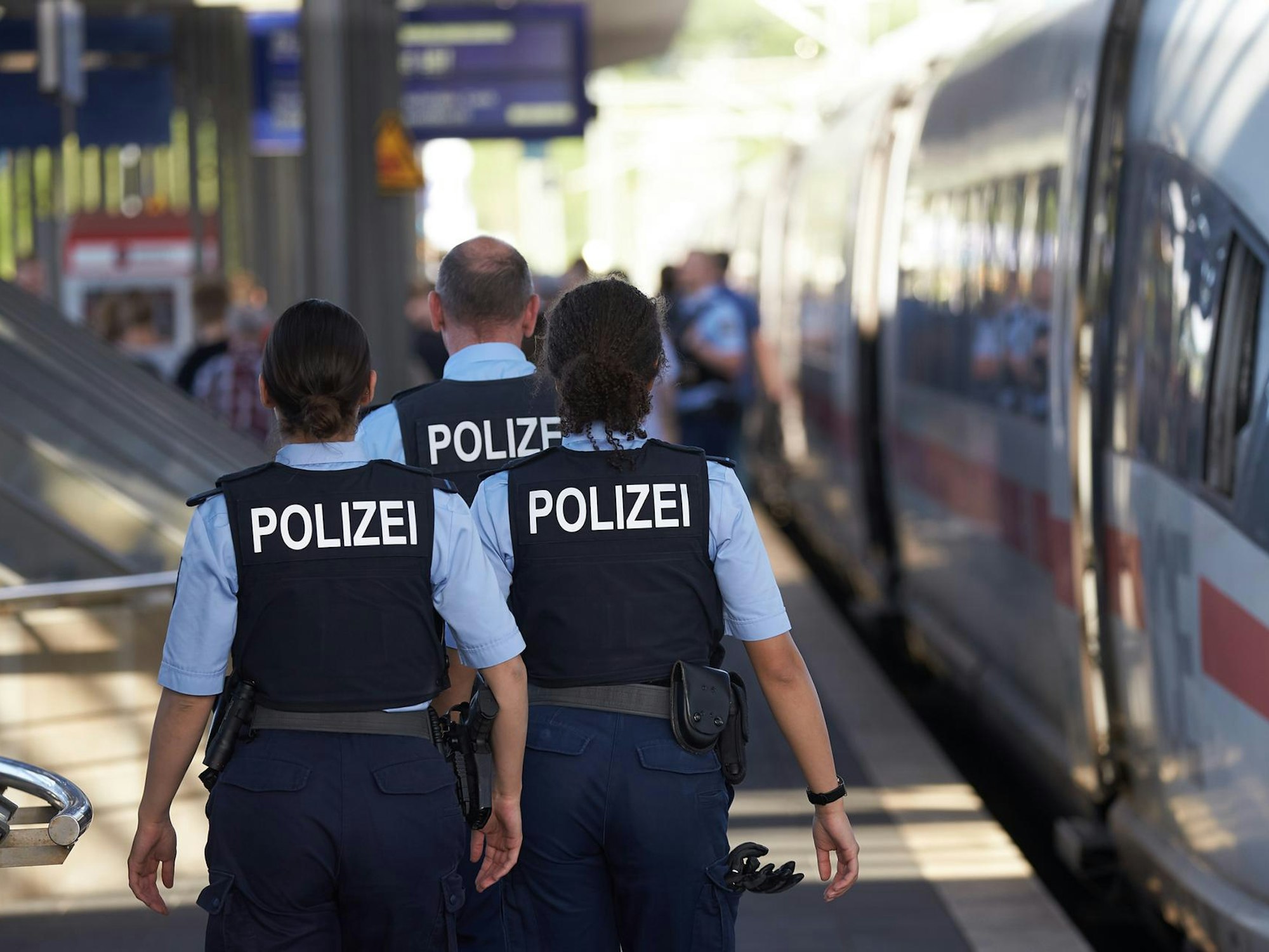 Polizisten gehen an einem Bahnsteig entlang.
