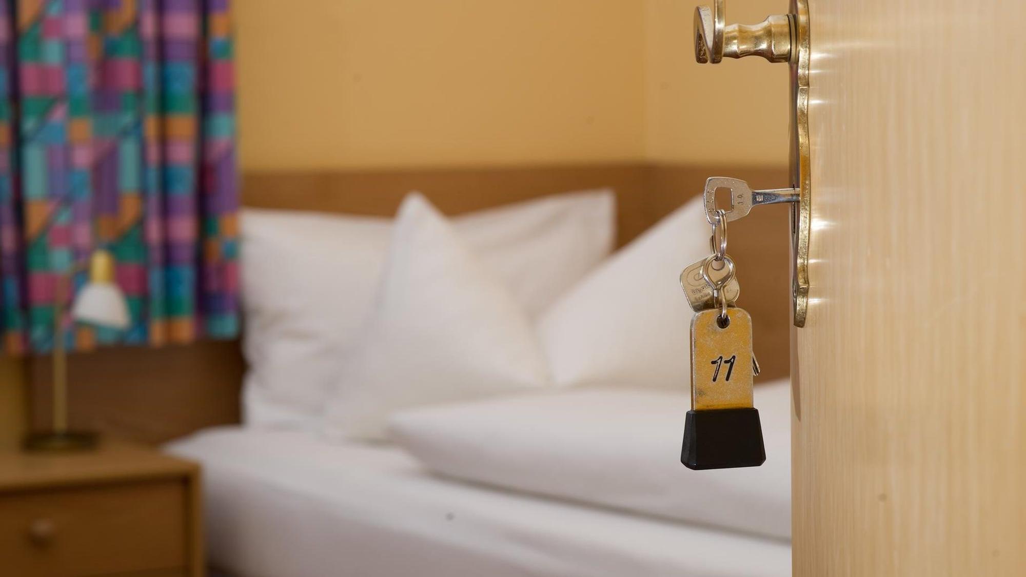Köln: Die Tür eines Hotelzimmers öffnet sich und ein Hotelbett ist zu sehen. In Köln ist ein Streit im Hotelzimmer eskaliert.
