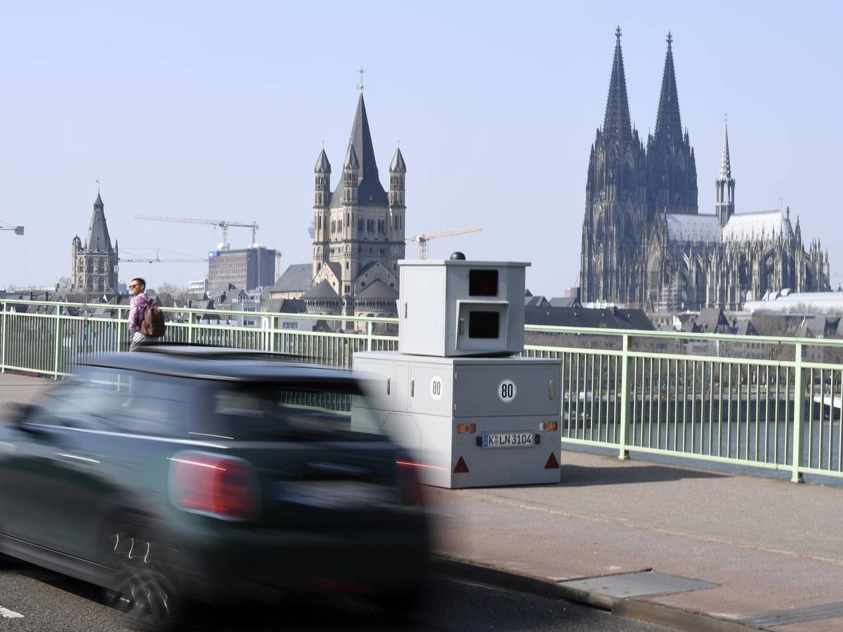 Eine Blitzanlage steht auf einer Brücke, im Hintergrund der Kölner Dom.
