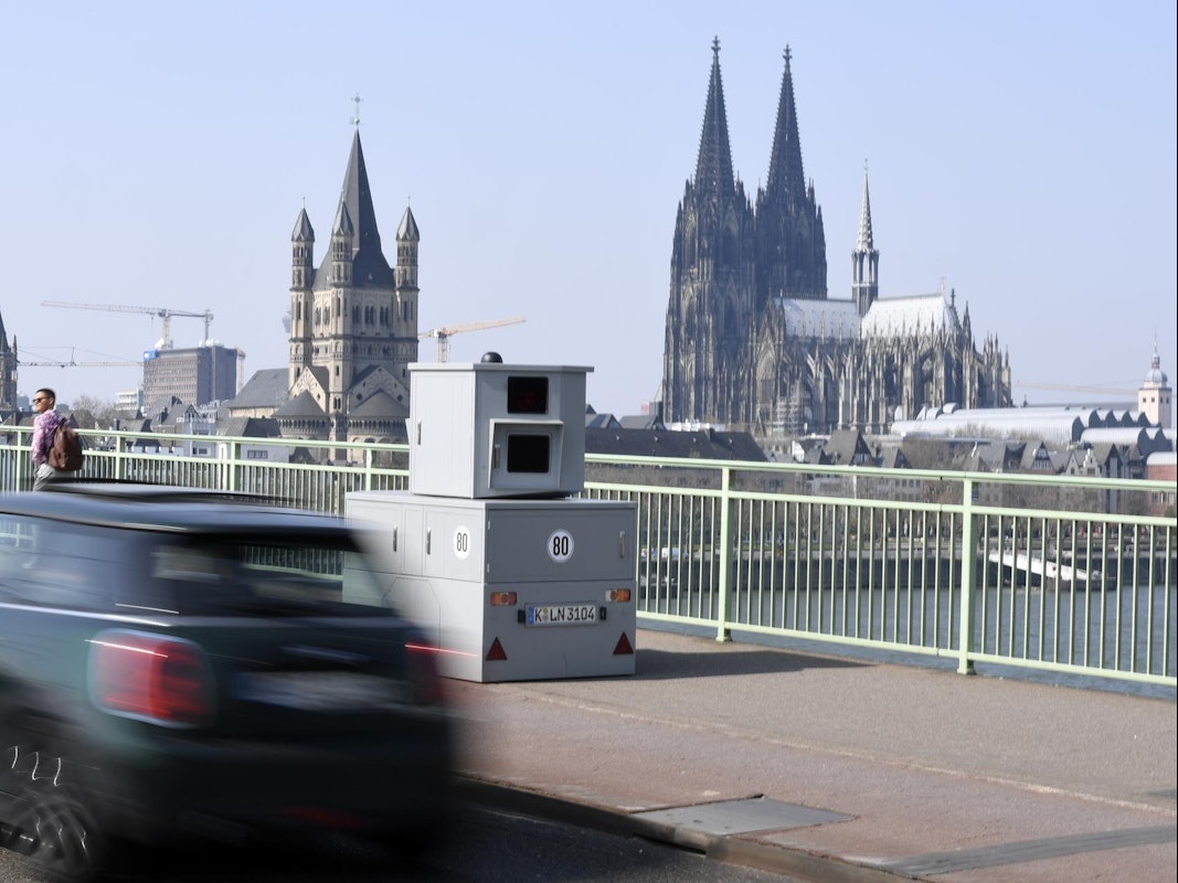 Eine Blitzanlage steht auf einer Brücke, im Hintergrund der Kölner Dom.
