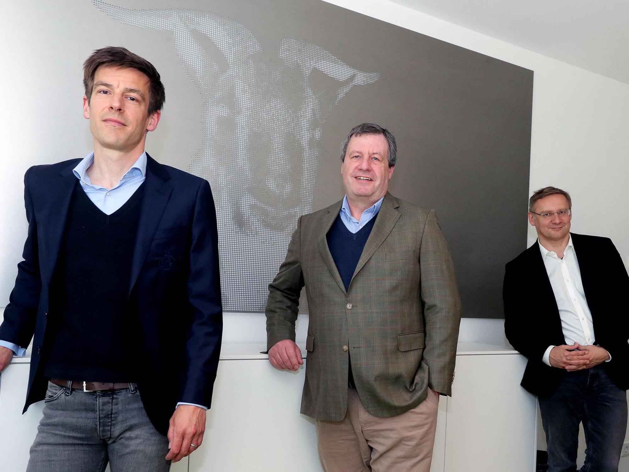 FC-Präsident Werner Wolf (Mitte) mit seinen beiden Vize-Präsidenten Eckhard Sauren (r.) und Carsten Wettich stehen vor einem Geißbock-Bild.