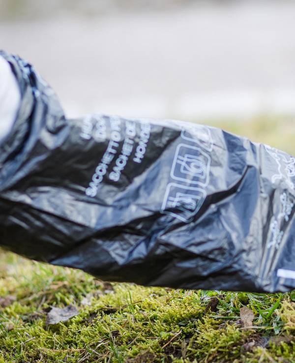 Person entfernt Hundekot mit Tüte.