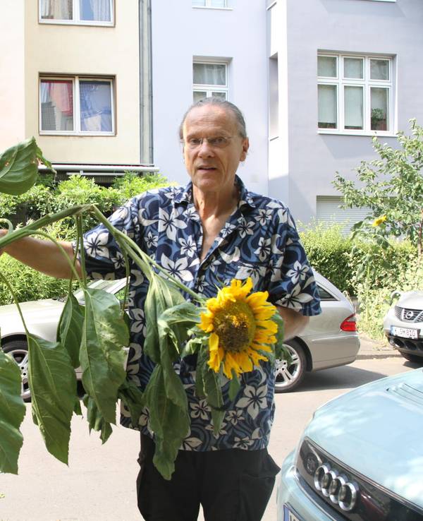 Ein Mann steht neben einer Sonnenblume.