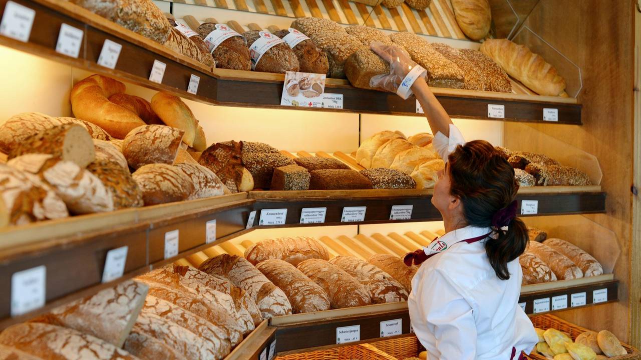Bäckereifachverkäuferin vor Brot- und Brötchensortiment (undatiert).