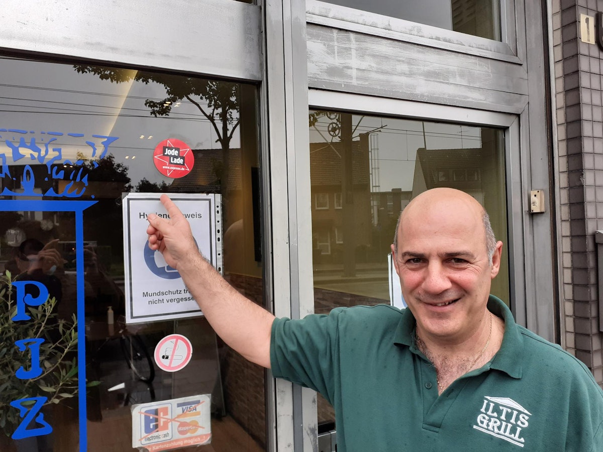 Christos Iliadis vom Iltis Grill zeigt den Aufkleber Jode Lade an seinem Imbiss.