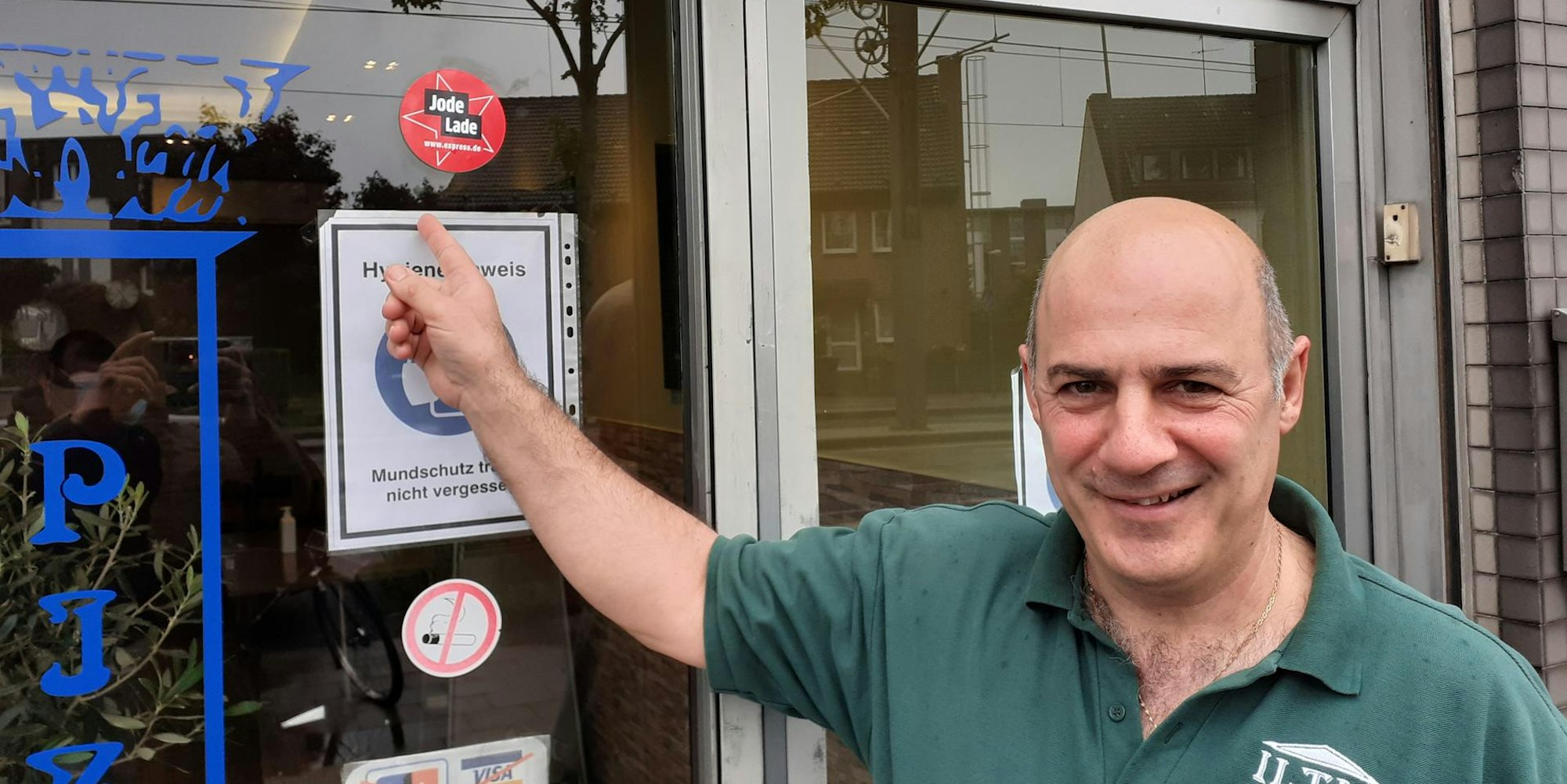 Christos Iliadis vom Iltis Grill zeigt den Aufkleber Jode Lade an seinem Imbiss.