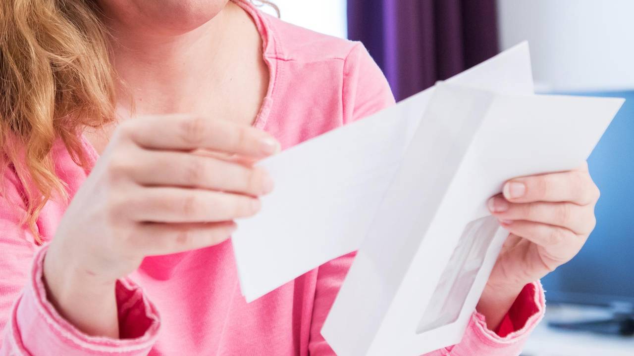 Eine Frau öffnet einen Briefumschlag.