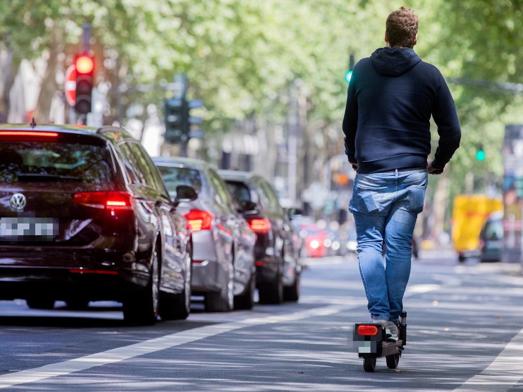 Ein Mann fährt in Köln auf einem E-Scooter.