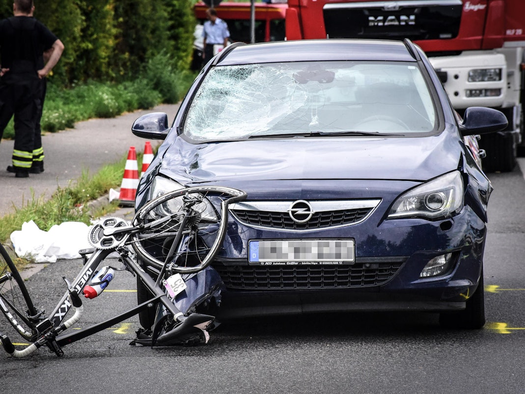 Unfallstelle: Ein verbogenes Rennrad vor einem Auto.