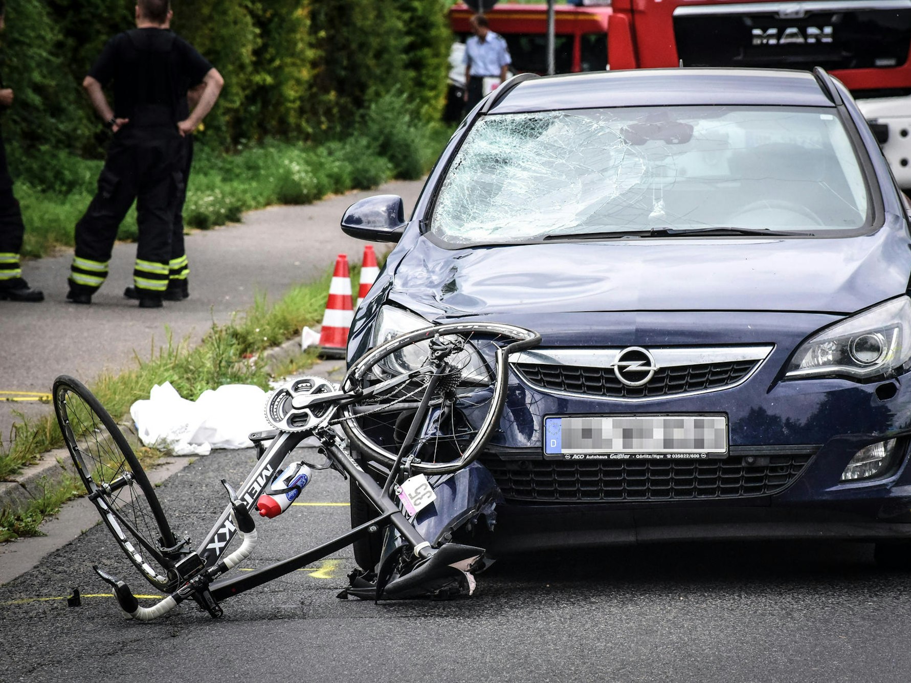 Unfallstelle: Ein verbogenes Rennrad vor einem Auto.